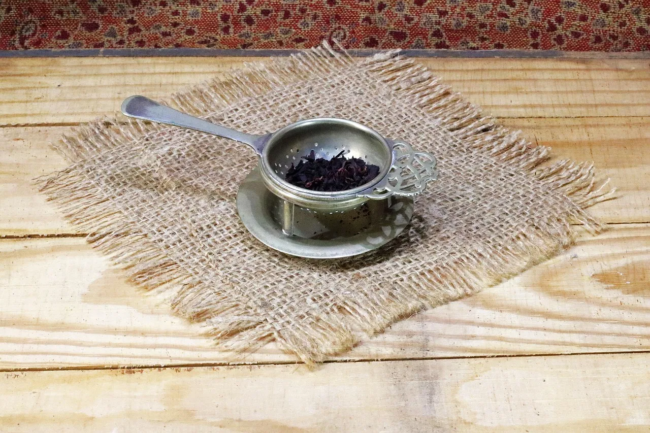 Ein Teesieb aus Messing auf einer Untertasse auf einem Holztisch