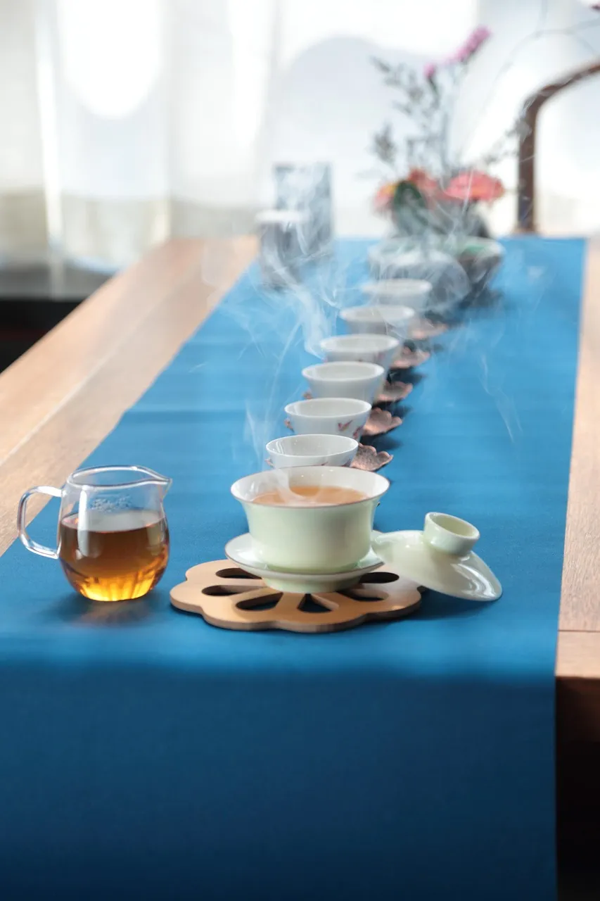 Eine Reihe weißer Verkostungstassen auf einem blauen Tuch in einem Teehaus in Chengdu